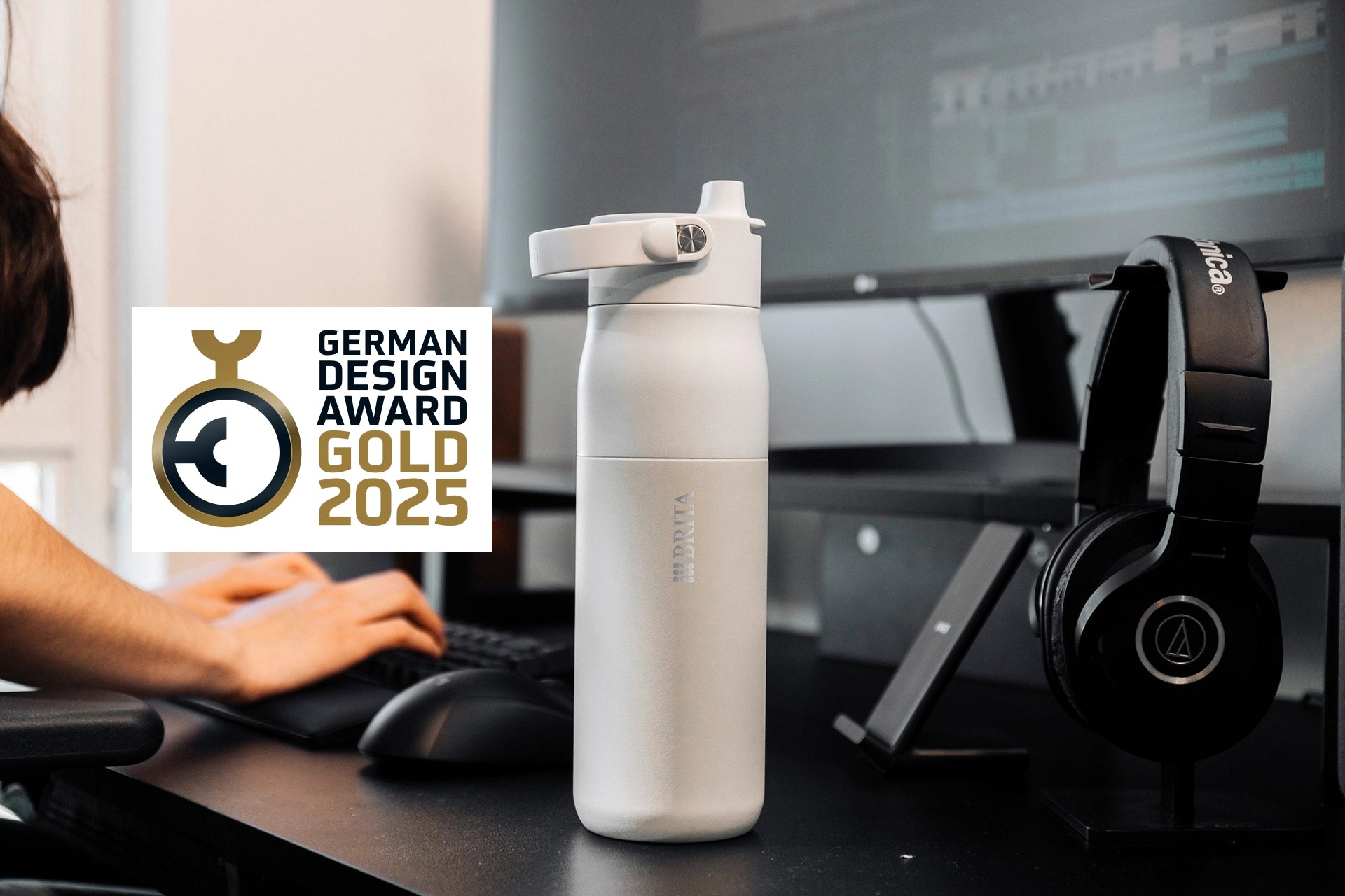 White BRITA LARQ Bottle displayed on a desk with German Design Award Gold 2025 logo