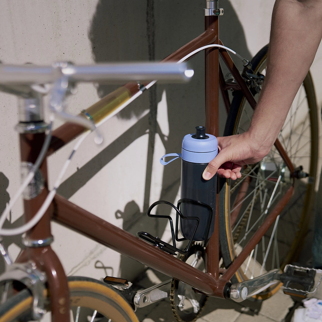 A person putting BRITA water filter bottle Model Active in blue in a bicycle