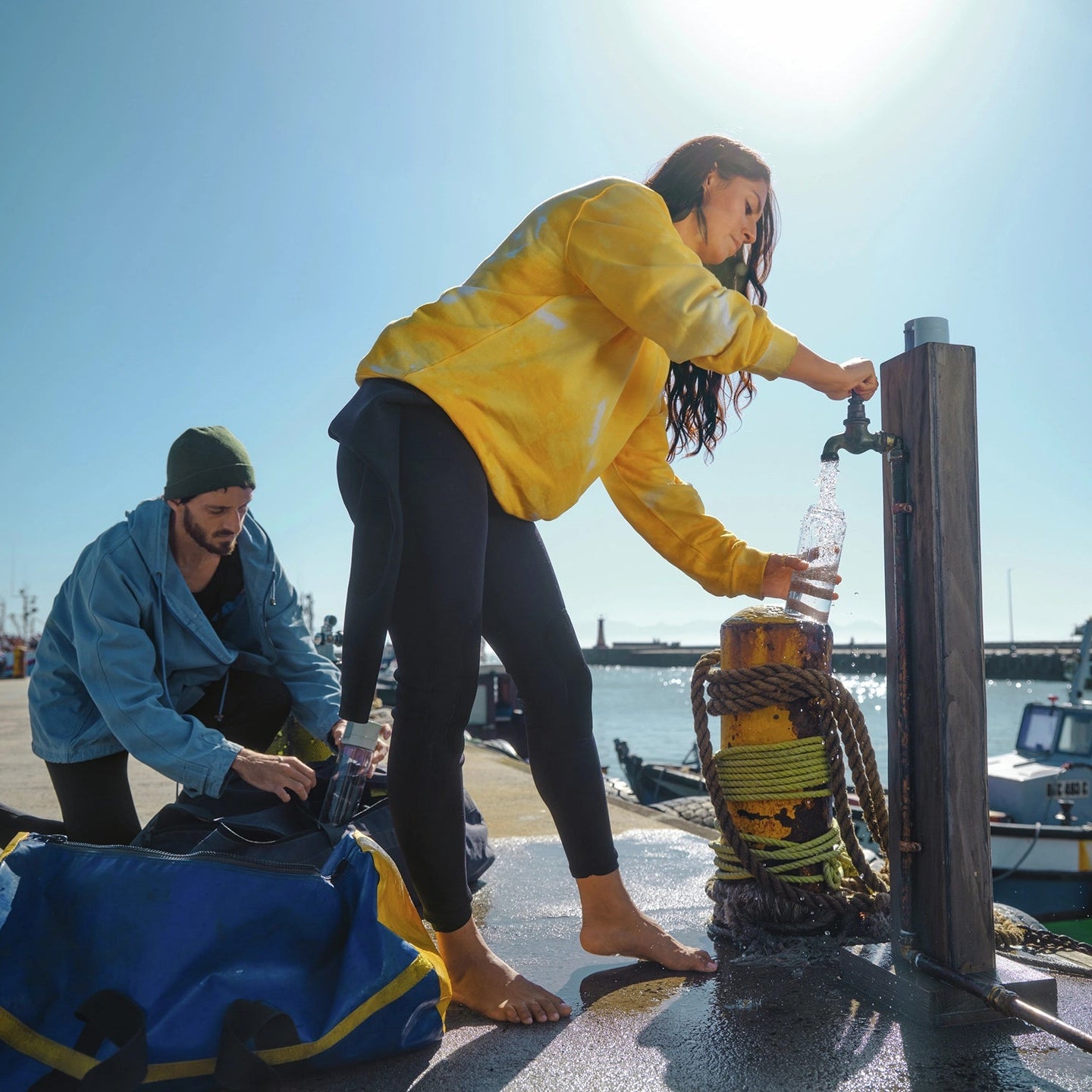 Twee mensen op een steiger aan het water; één van hen vult een BRITA-filter met water uit de kraan filter Fles Model Vital.