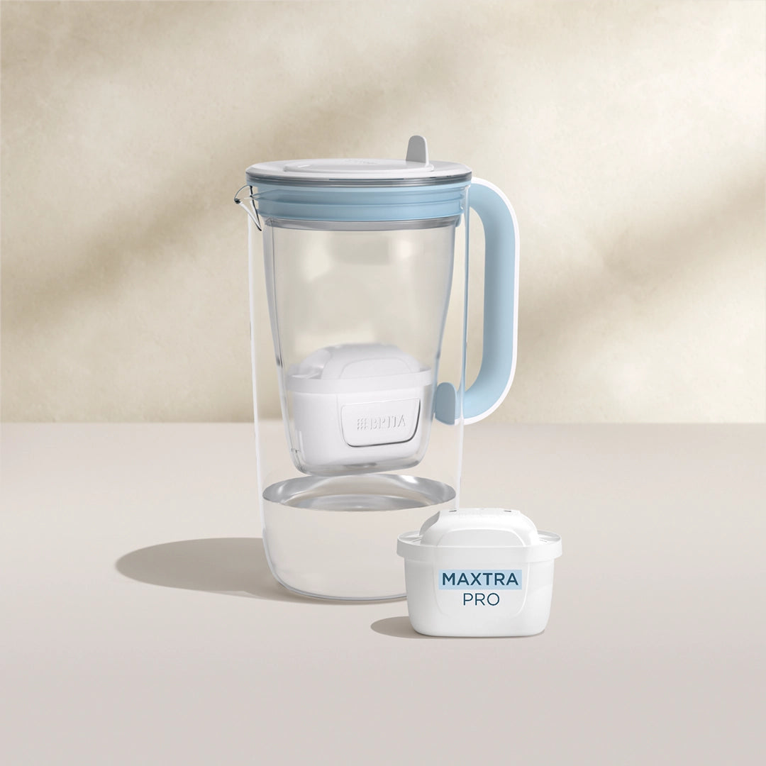 Een water filter Glazen waterfilterkan in blauw op een beige achtergrond