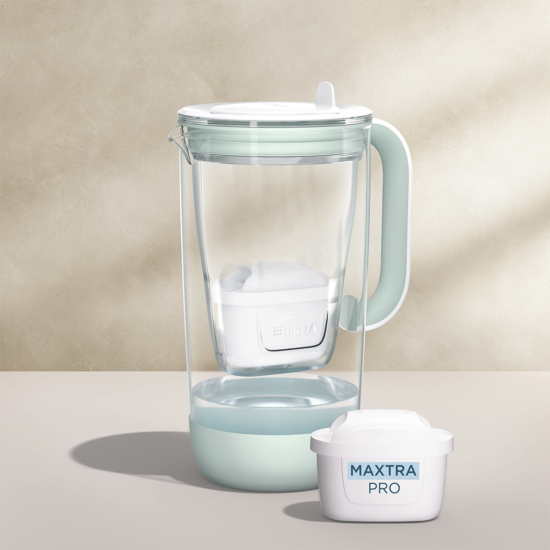 Een water filter Glazen waterfilterkan in het groen op een beige achtergrond