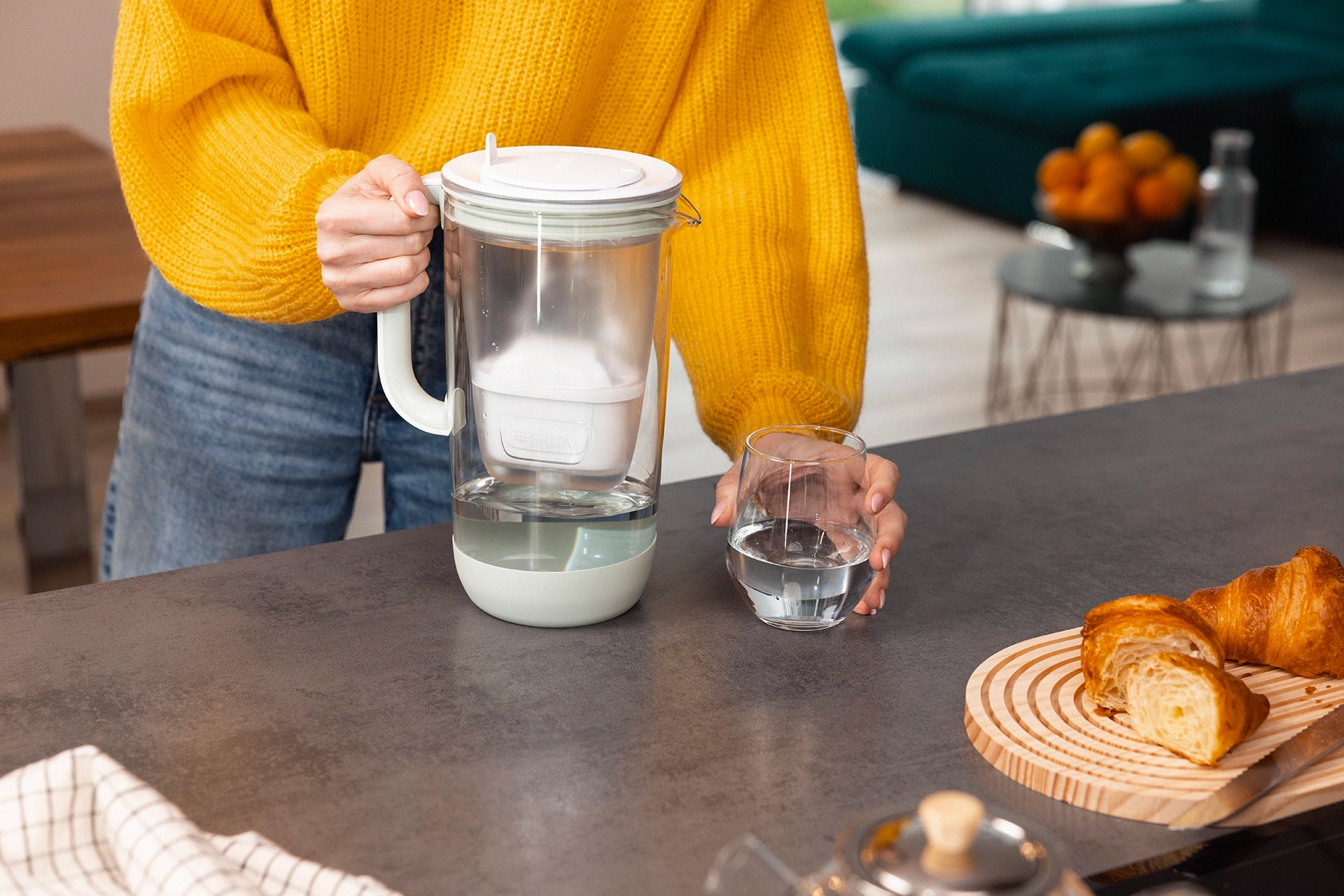 Green BRITA Glass Jug and a glass of filtered water on a kitchen counter.
