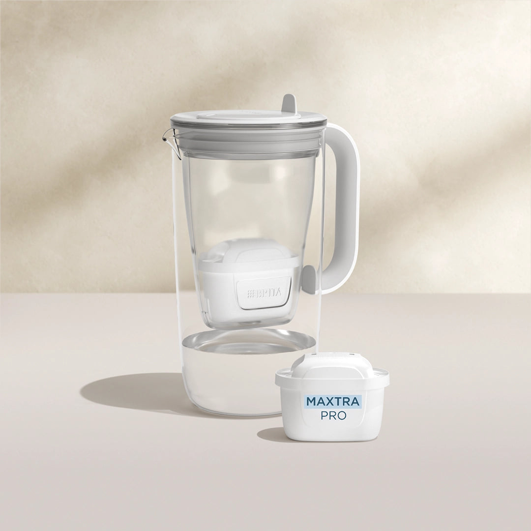 Een water filter Glazen waterfilterkan in grijs op een beige achtergrond