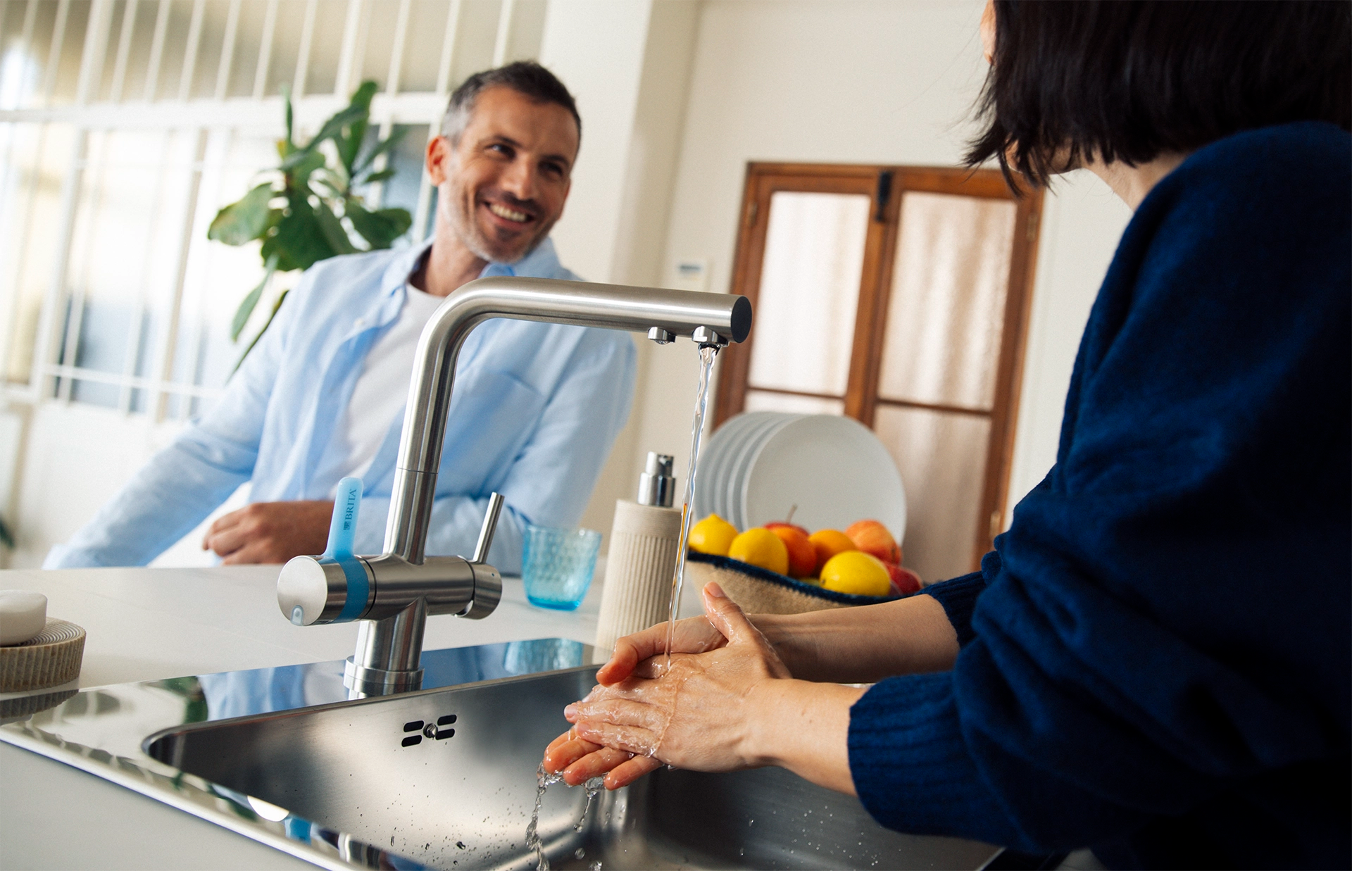 Person washing hands under a BRITA 3-way rectangular kitchen tap.